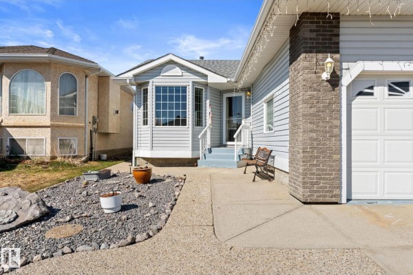 Close-up of the entrance to a light blue house with a bay window and a bench. - 13308 155 Av Nw, Edmonton