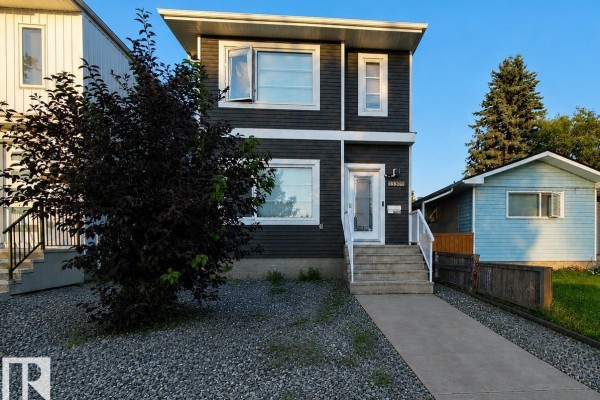 View of a dark grey house with a concrete walkway and lawn in front. - 13309 104 St Nw, Edmonton