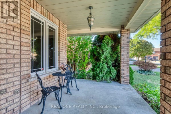 View from a covered porch with a wrought iron table and chairs looking out to the street. - 1332 Greenwood Crescent, Oakville