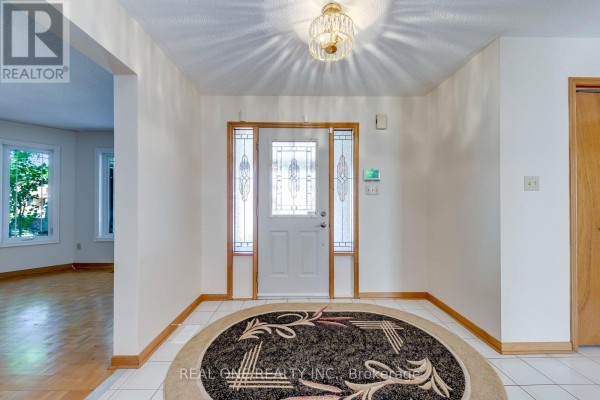 Interior foyer with white tiled floor, a round patterned rug, and a glass-panelled front door. - 1332 Greenwood Crescent, Oakville