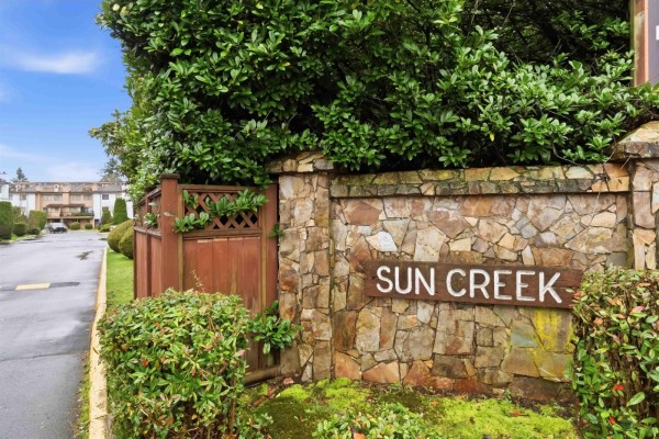 Stone monument sign for Sun Creek with surrounding trees and bushes. - 13323 71b Avenue, Surrey