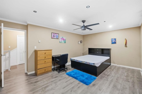 Bedroom with beige walls, queen bed, desk, dresser, and ceiling fan. - 13323 71b Avenue, Surrey