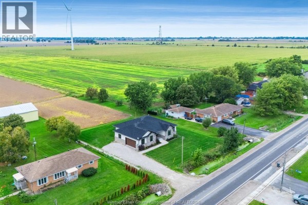Aerial view of a residential property surrounded by green fields and distant wind turbines. - 1333 County Road 31, Lakeshore