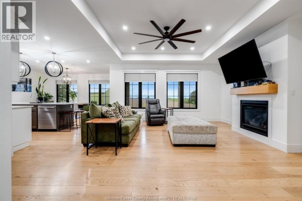 Open-concept living area with hardwood floors, fireplace, large windows, and sectional sofa. - 1333 County Road 31, Lakeshore