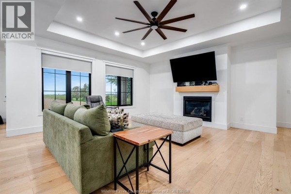 Living room featuring a fireplace, mounted television, sectional sofa, and a large ceiling fan. - 1333 County Road 31, Lakeshore