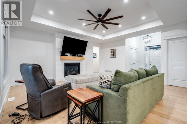 Living room with light wood floors, green sofa, recliner, fireplace, and views through windows. - 1333 County Road 31, Lakeshore