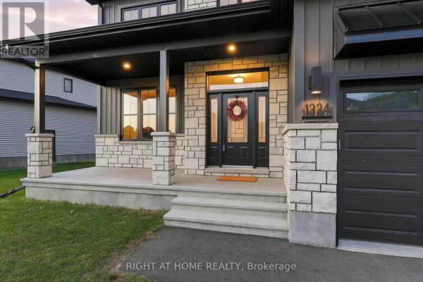 Side view of a modern house with a two-car garage and manicured lawn. - 1334 Fribourg Street, Russell