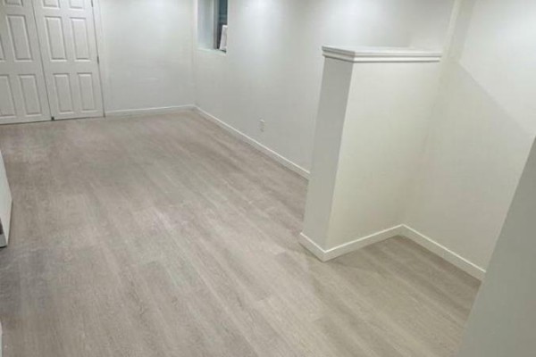 Empty room with light grey wood-look laminate flooring and white walls. - 1336 Avenue T Avenue, Ottawa