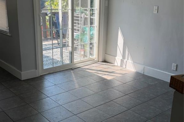 Room with grey tiled floor and sliding glass doors leading to a patio, with sunlight streaming in. - 1337 Assumption Street Unit# 1, Windsor
