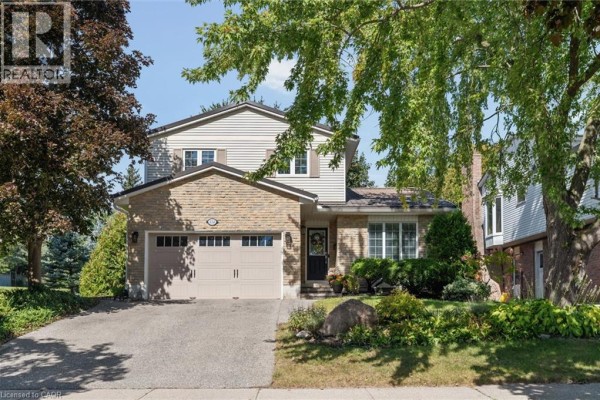 Exterior view of a two-story house with a beige garage door and light brown brick accents. - 134 Bechtel Drive, Kitchener