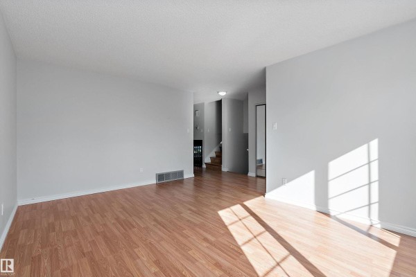 Dining area with a wooden table and chairs next to a kitchen, with a staircase and railing. - 134 Cameron Cr, Wetaskiwin