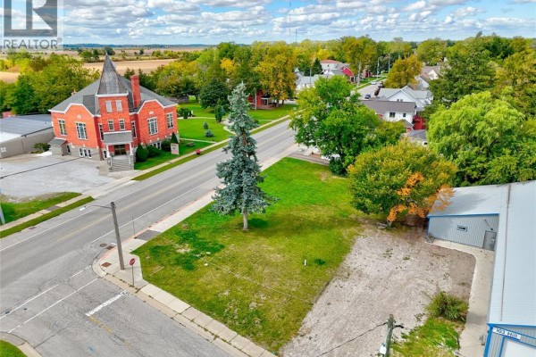 Aerial view of a street corner lot with a building and trees, showing surrounding homes. - 134 County Rd 34 W., Cottam