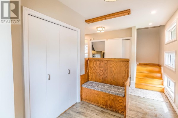 Entryway with white double doors, a wooden bench with patterned cushion, and stairs leading to a second floor. - 134 Florwin Dr, Sault Ste  Marie