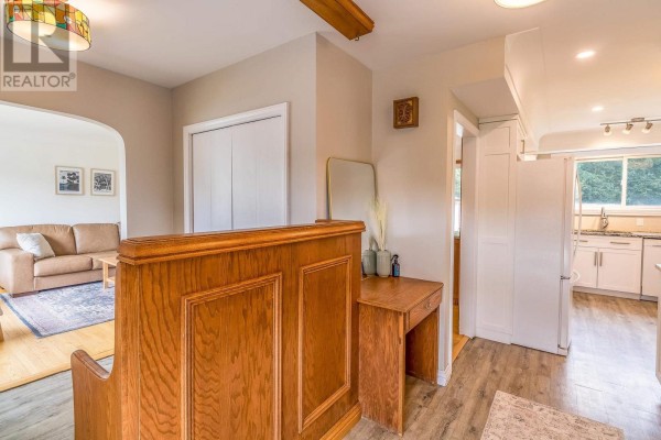 View of a living room and kitchen from the entryway, featuring a sofa, cabinets, and a wooden partition. - 134 Florwin Dr, Sault Ste  Marie