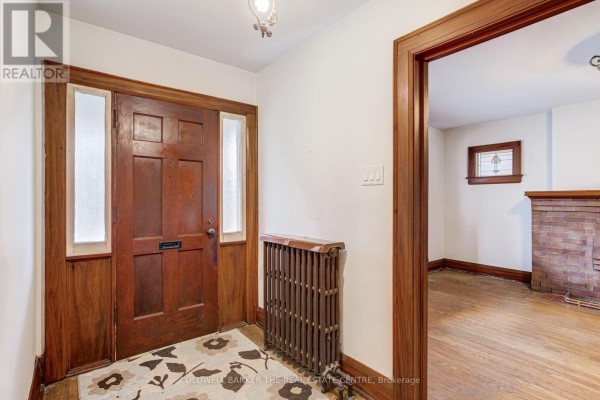 Interior entryway with dark wood trim, radiator, and doorway to living room. - 134 Harvie Avenue, Toronto