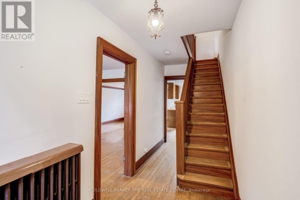Interior hallway with staircase, wood trim, and doorways to other rooms. - 134 Harvie Avenue, Toronto