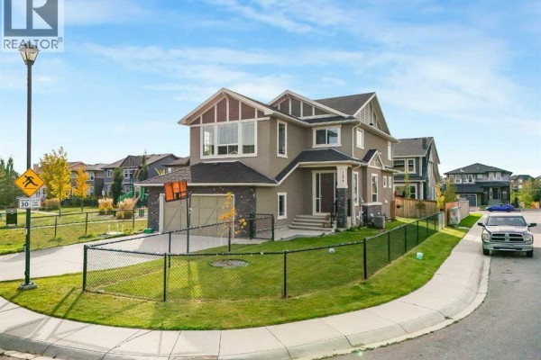 View of a two-story house with a fence, lawn, and nearby houses. - 134 Kinniburgh Lane, Chestermere