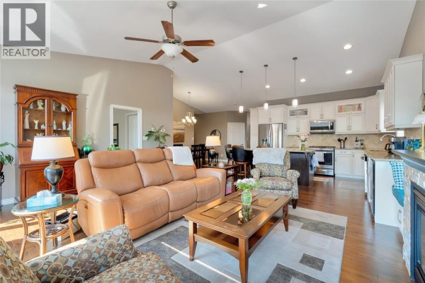 Living room with stone fireplace, large television, and patterned armchairs. - 1340 Aspenshore, Windsor