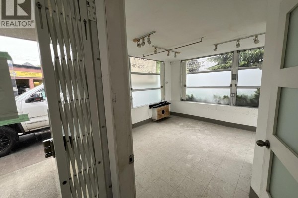 Commercial building exterior with signage, parking lot, and surrounding trees. - 1340 W 4th Avenue, Vancouver