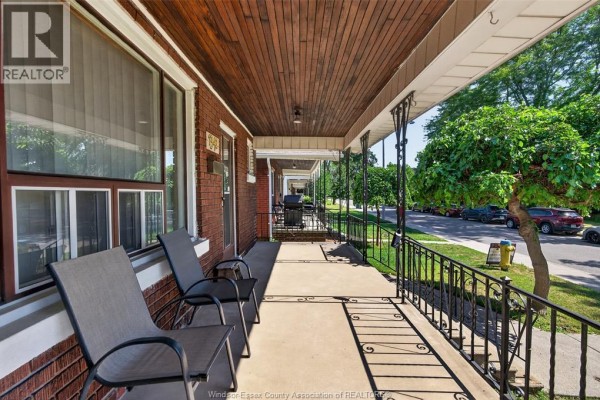 View from the covered porch looking down the street, showing two chairs and a railing. - 1342 Hall Avenue, Windsor