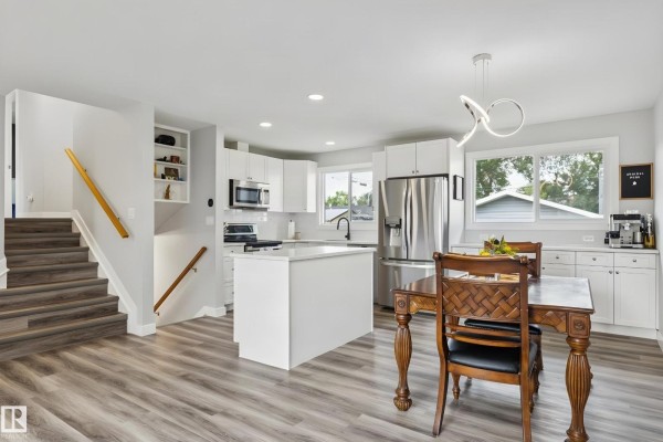 Interior view of the entrance hallway with a white door, grey walls, and wood-look laminate flooring. - 13428 117a Av Nw, Edmonton