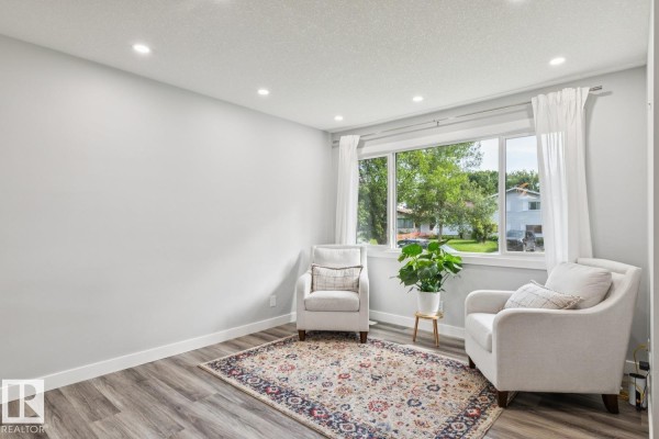 Open concept kitchen and dining area with white cabinetry, stainless steel appliances, and a wooden dining table. - 13428 117a Av Nw, Edmonton