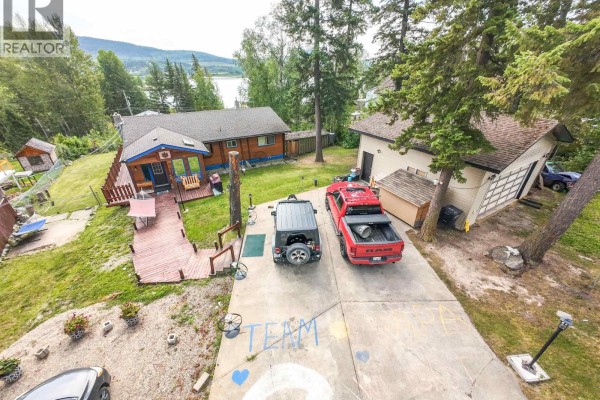 Aerial view of a house with a lake and hills in the background. - 1344 Lakeview Drive, Quesnel