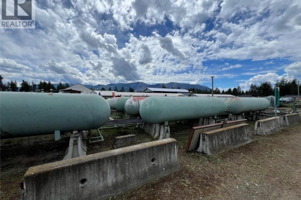 View of large green propane tanks on stands in yard with concrete barriers. - 1345 Cardy Drive, Scotch Creek