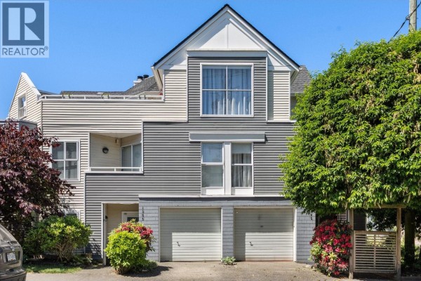 Front exterior of a townhouse with light grey and white siding and two double garage doors. - 1345 Woodland Drive, Vancouver