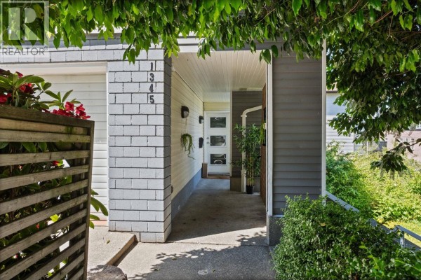 Covered entryway to a townhouse with white brick and grey siding, showing unit numbers 1345. - 1345 Woodland Drive, Vancouver