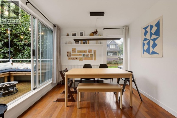 Dining room with white walls, hardwood floors, a wooden table and bench, and sliding glass doors to a deck. - 1345 Woodland Drive, Vancouver
