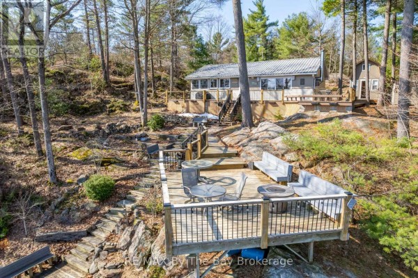 Deck area with seating and a view of the house surrounded by trees and rocks. - 1346 Is 980/deer, Georgian Bay