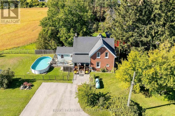 Brick house with a light blue addition, fenced yard, and oval swimming pool. - 1346 Penetanguishene Road, Springwater