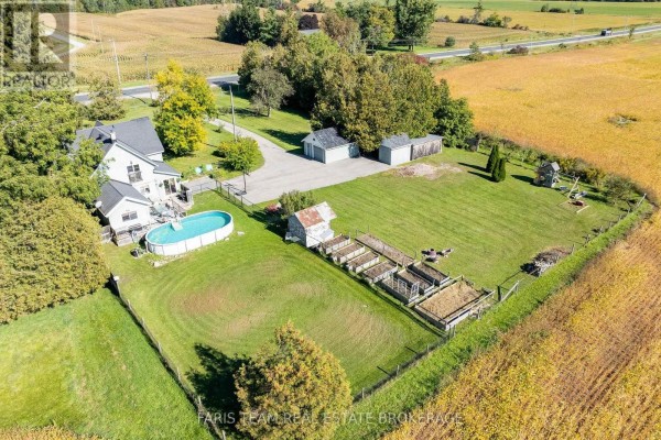 Aerial view of a residential property with a pool, garden beds, and outbuildings. - 1346 Penetanguishene Road, Springwater