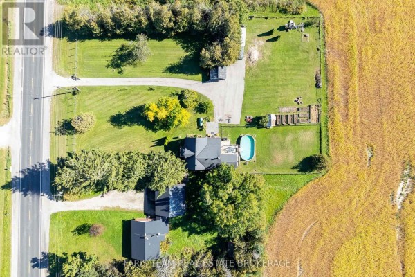 Overhead view of a property with a house, pool, garden, and surrounding agricultural fields. - 1346 Penetanguishene Road, Springwater
