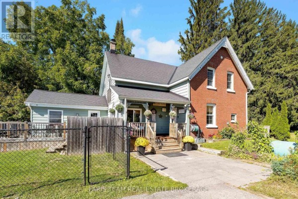 Front view of a red brick house with a light blue siding addition and a covered porch. - 1346 Penetanguishene Road, Springwater