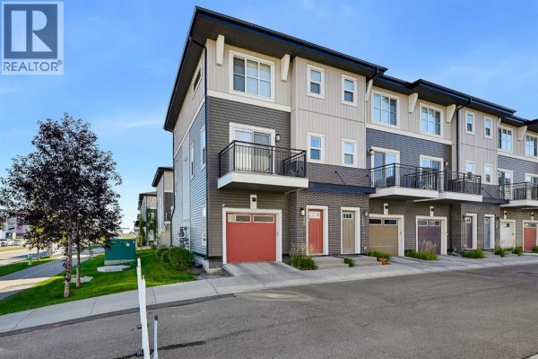 Street view of a townhouse complex with multiple units and garages. - 135, 30 Cornerstone Manor Ne, Calgary