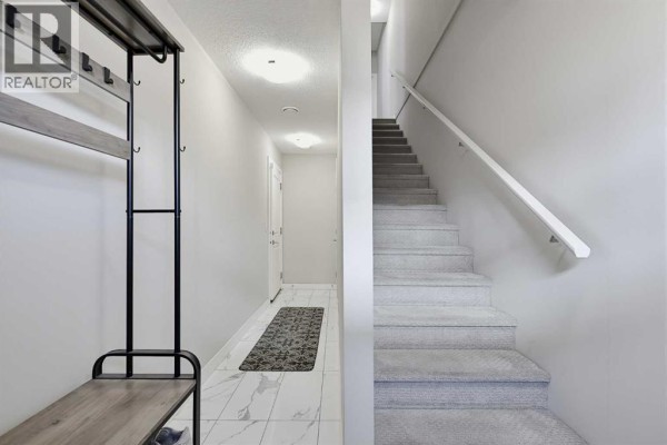 Interior entryway with light gray walls, tiled floor, and carpeted stairs. - 135, 30 Cornerstone Manor Ne, Calgary