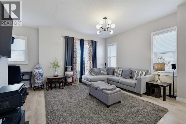 Living room with gray sectional sofa, ottoman, large rug, and windows. - 135, 30 Cornerstone Manor Ne, Calgary