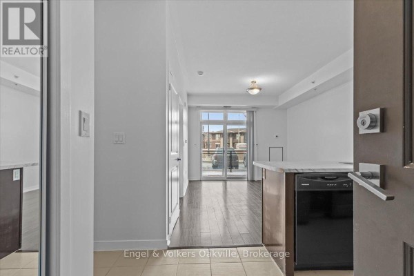 View into living room and balcony from apartment entryway with light wood floors. - 135 - 5010 Corporate Drive, Burlington