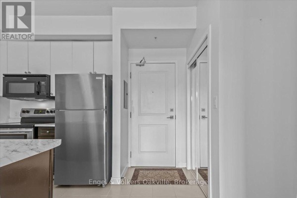 View of apartment kitchen with stainless steel appliances and hallway entrance with mirrored closet. - 135 - 5010 Corporate Drive, Burlington