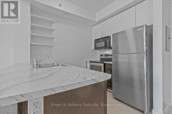 Apartment kitchen with stainless steel refrigerator, microwave, stove, sink, and open shelving. - 135 - 5010 Corporate Drive, Burlington