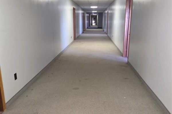 Long, carpeted interior hallway with white walls and multiple doors. - 135-161 Main Street, Burin