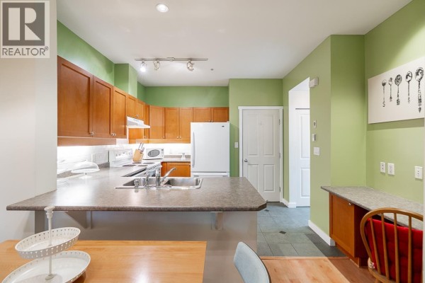 Stacked white washer and dryer in a small laundry closet with white doors. - 135 18 Jack Mahony Place, New Westminster