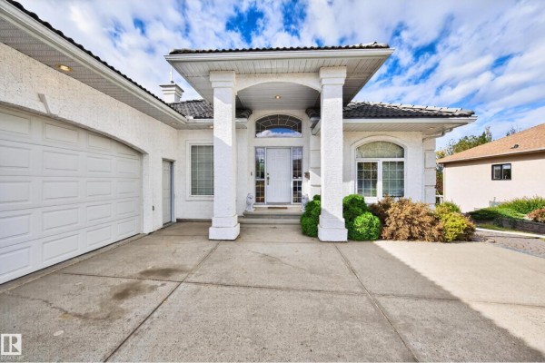 Close-up of the white house entrance with columns, arched windows, and a double garage door. - #135 52304 Rge Road 233, Rural Strathcona County