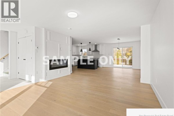 Open concept living area with a fireplace, white walls, light wood floors, and a modern kitchen. - 135 Beau Domaine Court, Dieppe