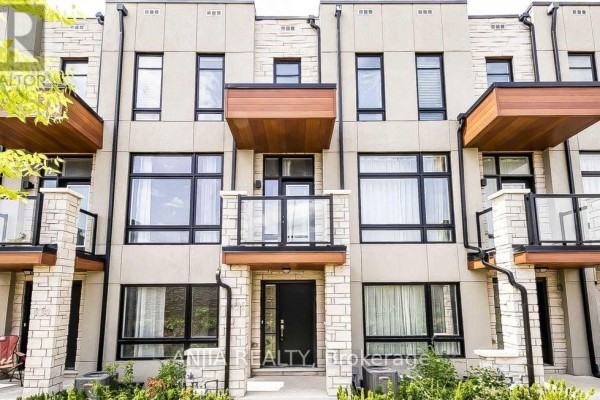 Front view of a beige townhouse with stone accents, large windows, and balconies. - 135 Carpaccio Avenue, Vaughan