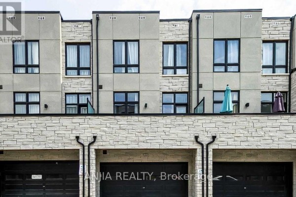 Upper facade of townhouses showing multiple windows and balconies above garage doors. - 135 Carpaccio Avenue, Vaughan