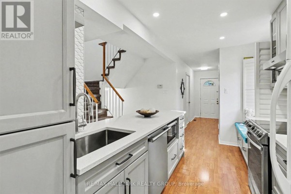 Modern white kitchen with a large island, stainless steel sink, and subway tile backsplash. - 135 Evelyn Avenue, Ottawa