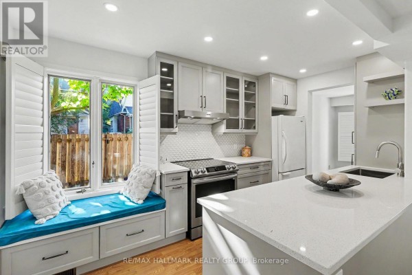 Kitchen window with a built-in bench seat and white plantation shutters, overlooking greenery. - 135 Evelyn Avenue, Ottawa